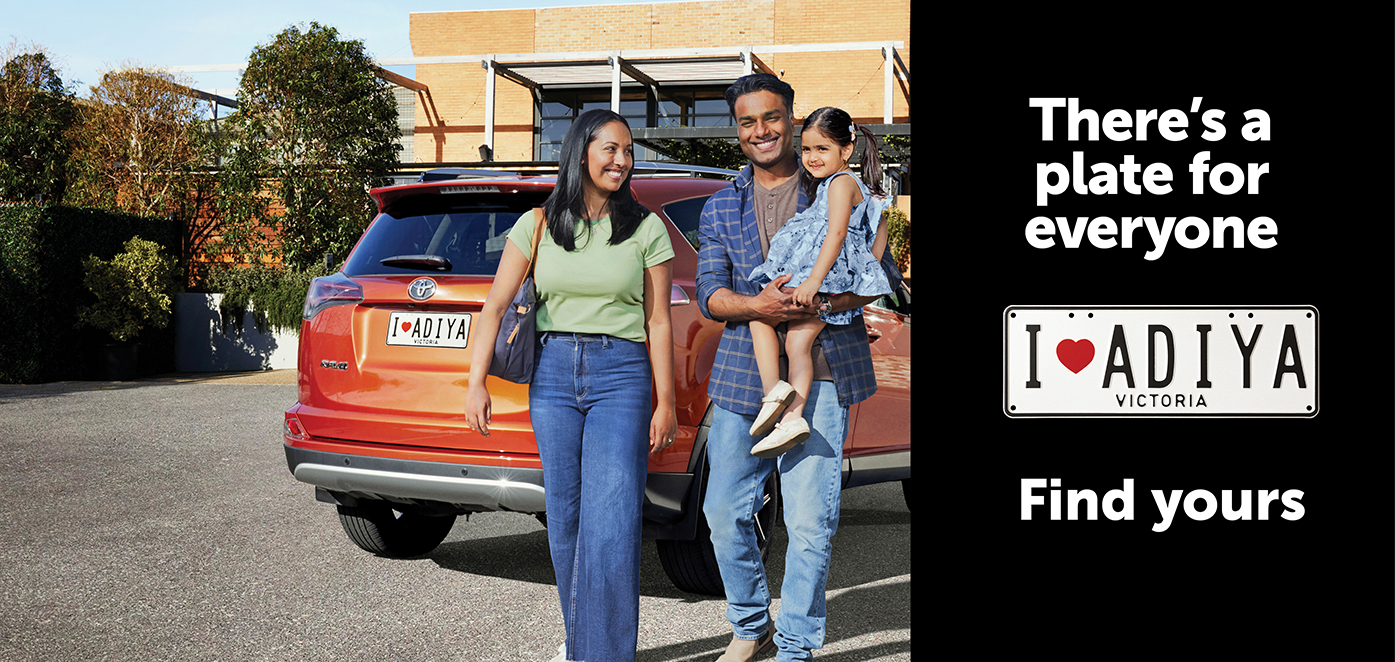 Couple with child standing alongside their car with numberplate I(heart)ADIYA